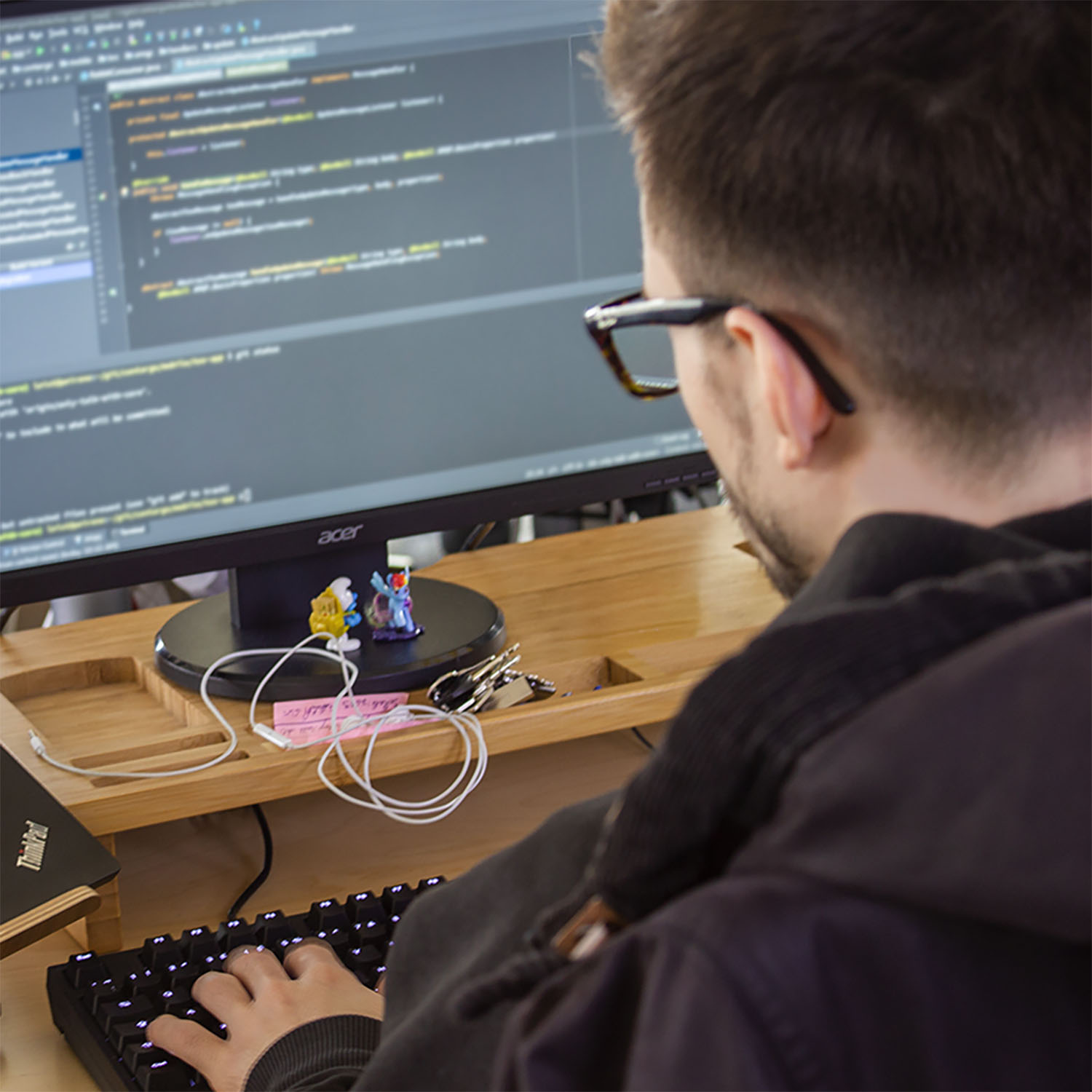 Entwickler programmiert an drei Bildschirmen mit ergonomischer Split-Tastatur.